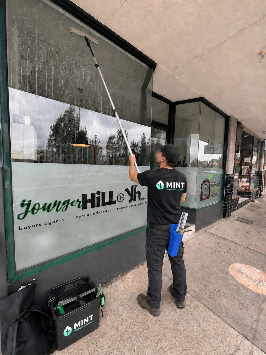 Mint Window Cleaning technician cleaning a Fairfield business storefront window with an extension pole